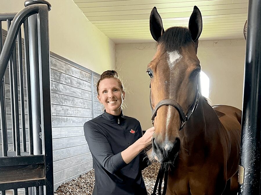 A woman standing next to a horse in a stable.