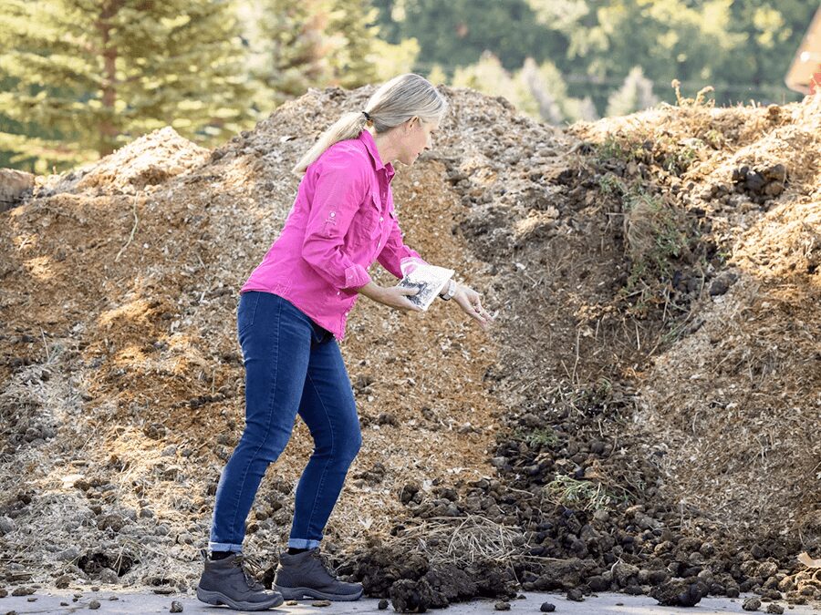 A woman in pink jacket standing next to pile of dirt.